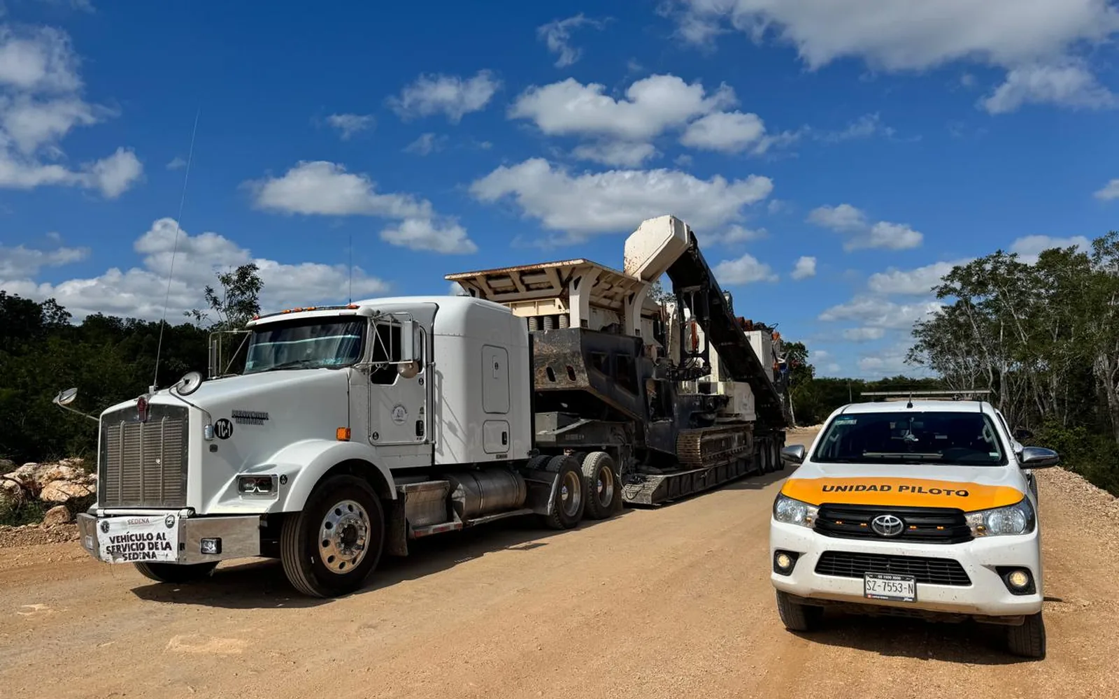 Tractocamión con lowboy trasladando una planta trituradora, escoltado por unidad piloto